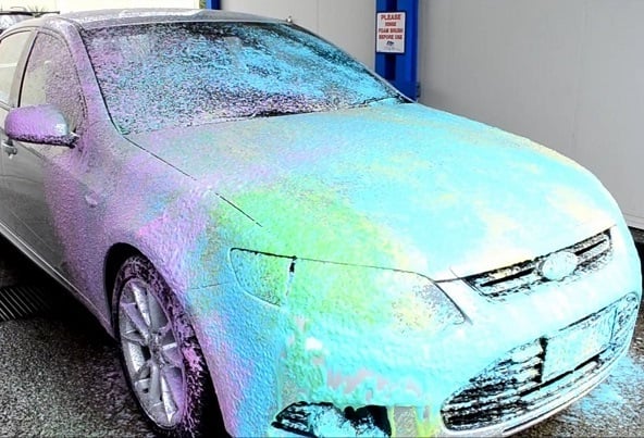 Foam-covered car in a self-serve wash bay
